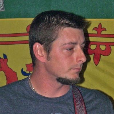 Man with short hair and goatee playing guitar.