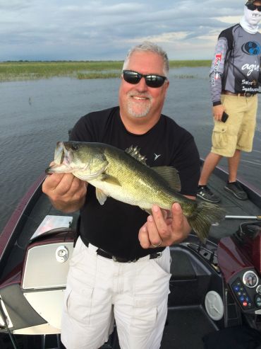 Man holding a largemouth bass on a fishing boat.