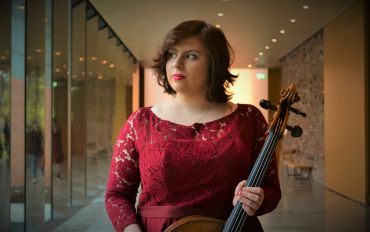 Woman in red lace dress holding a cello.