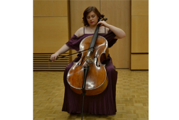 Woman playing cello in a concert hall.