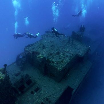 Scuba divers exploring a sunken shipwreck deep underwater.