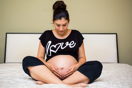 pregnant woman wearing a love t-shirt looking down at her belly