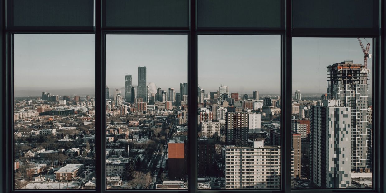 City skyline viewed through large window panes during daytime.