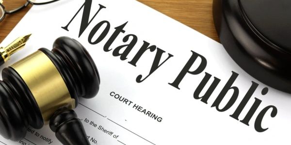 Notary Public document with gavel and glasses on wooden desk.