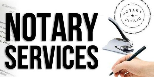 A hand signing documents with notary services text and stamp.