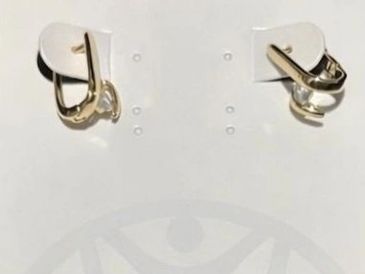 Two mismatched gold earrings displayed on a white card.