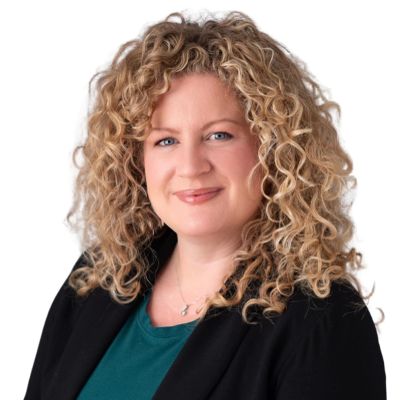 Professional woman with curly blonde hair wearing a black blazer and teal top.