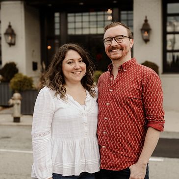 Smiling couple standing outside a building, posing for a photo.