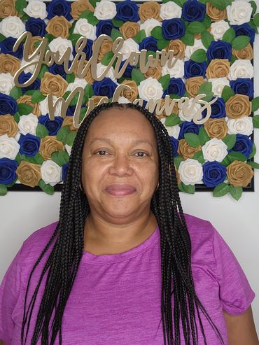 Woman with braided hair smiles in front of a floral backdrop.