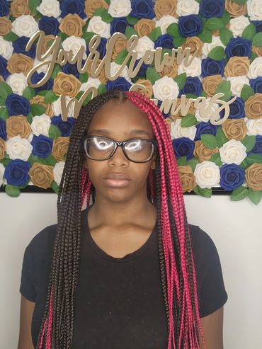 Young woman with long braided hair standing in front of a floral backdrop.
