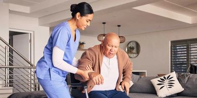 Nurse assisting elderly man from wheelchair with care and support.
