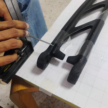 Persona reparando una pieza negra con herramientas.