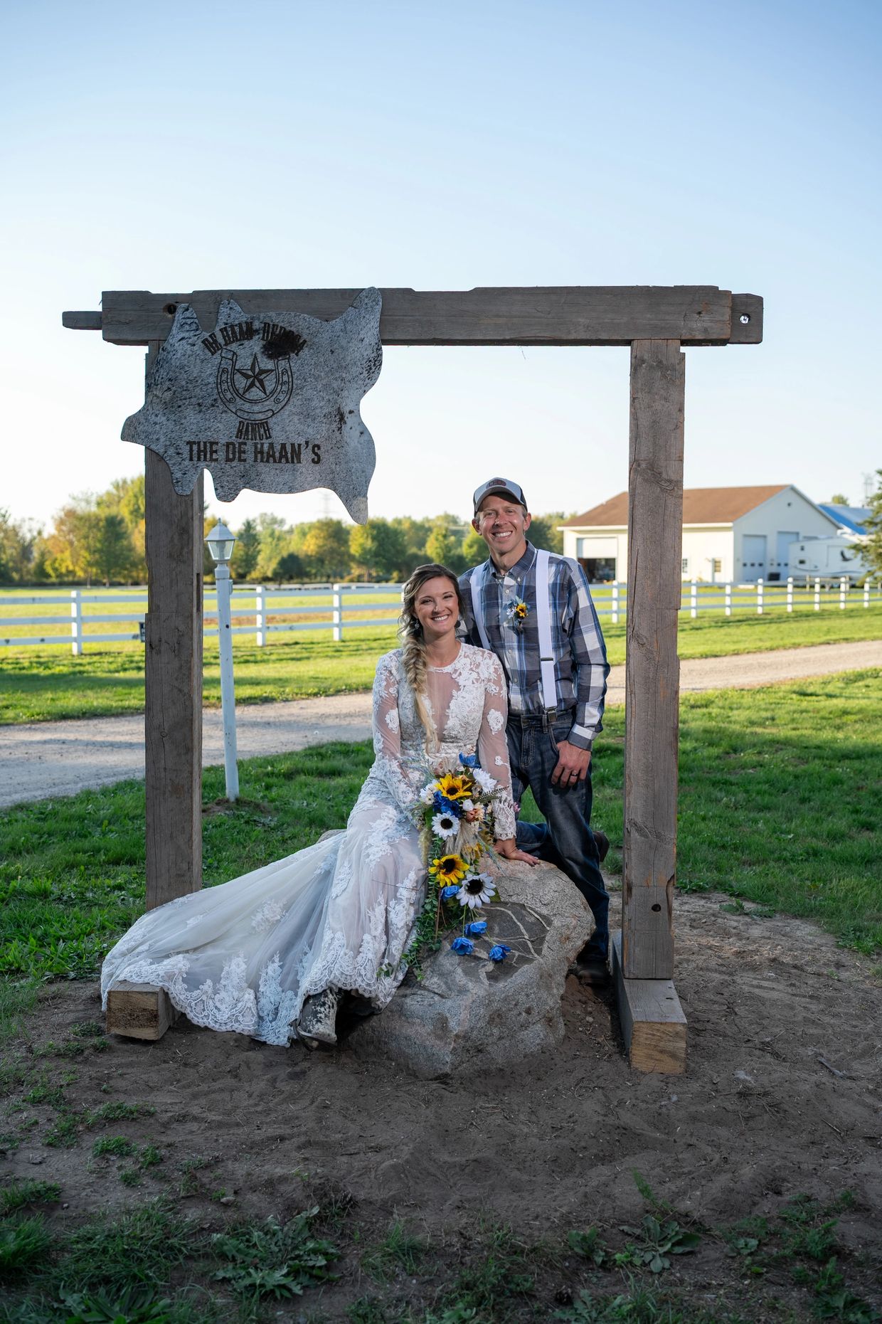 Happy couple in wedding attire at De Haan's Ranch sign outdoors.