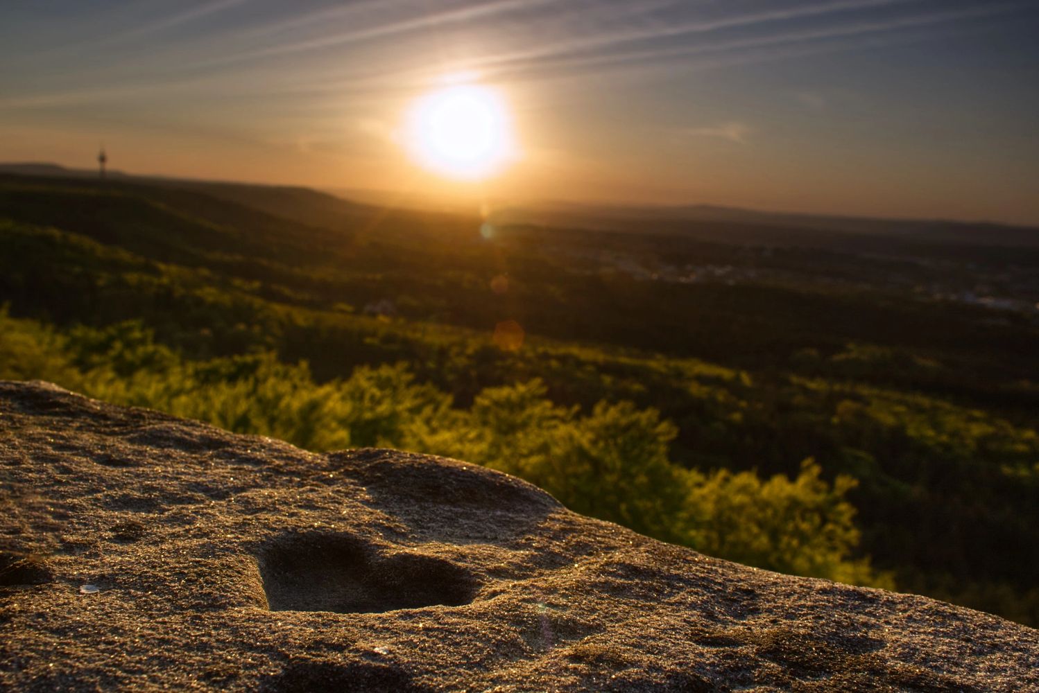  heart in the ground on a hill overlooking green fields while the sun sets.