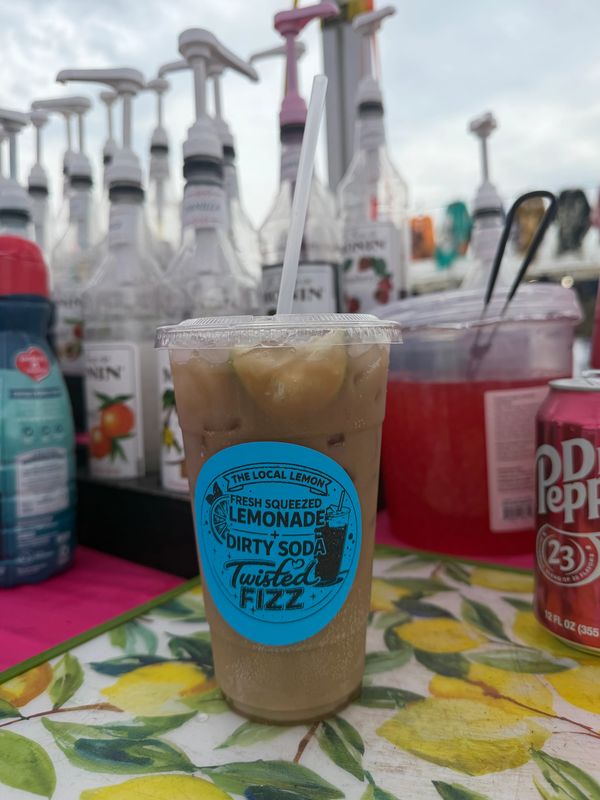 Iced lemonade soda drink with a straw on a lemon-themed table.