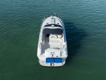 A white motorboat floating on calm water, viewed from above.