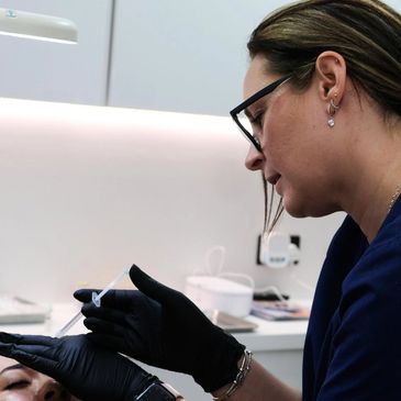 A professional wearing black gloves performs a facial treatment on a client.