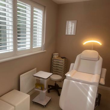 Cozy, modern treatment room with a white reclining chair and soft lighting.
