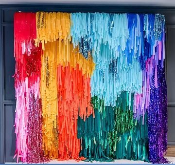 A vibrant, multicolored fringe backdrop with cascading strips and shiny accents.