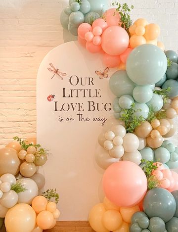 Decorative baby shower backdrop with pastel balloons and nature-themed accents.