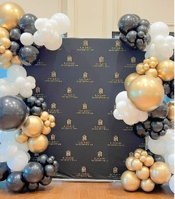Elegant balloon arch in black, white, and gold for a formal event.