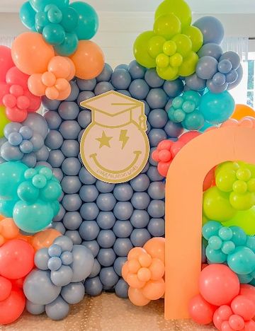 Colorful balloon arch with a graduation-themed smiley face centerpiece.