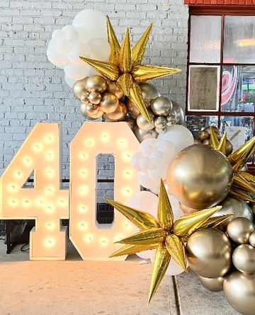 Illuminated number 40 decoration with gold and white balloons for a celebration.