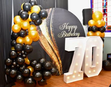 70th birthday party round backdrop with balloons and marquee numbers 