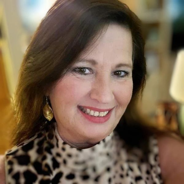 Smiling woman with leopard print top and gold earrings.