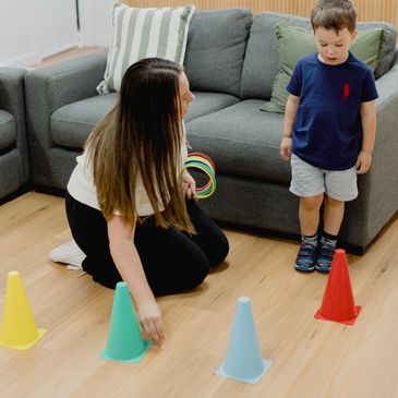 Woman playing a ring toss game with a young boy indoors.