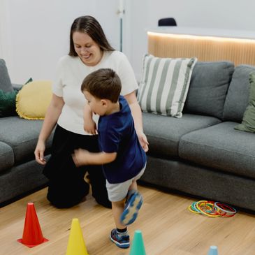 Child playing a ring toss game with an adult in a living room.