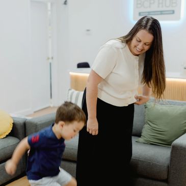 Woman smiling while playing with a child in a cozy living room.