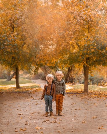 Dos niños sonrientes en un parque otoñal.
