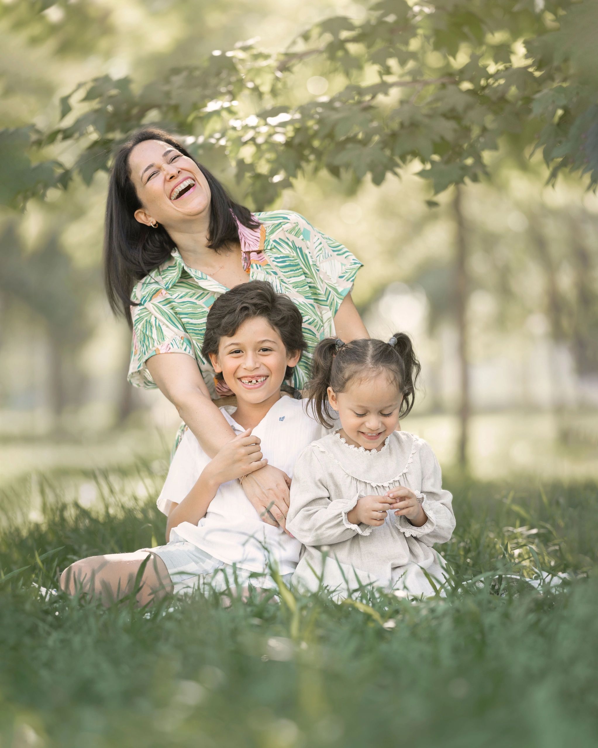 Madre feliz con sus hijos riendo en un parque.