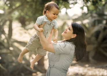 Madre feliz sostiene a su hijo pequeño en el aire.