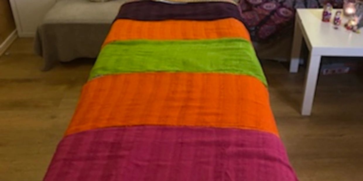 Colorful striped blanket on a massage table in a cozy room.