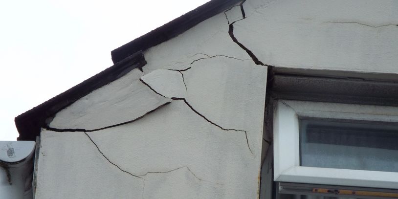 Cracks on the exterior wall near a window.