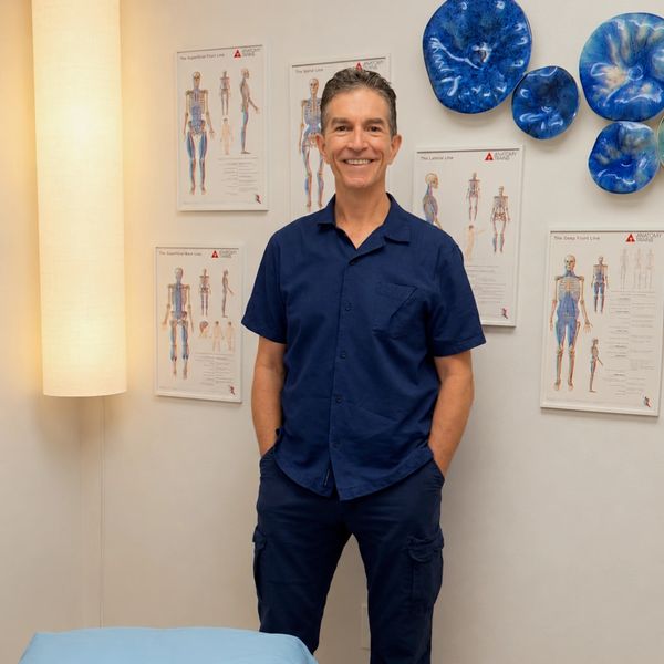 Smiling man in navy uniform in a clinic room.