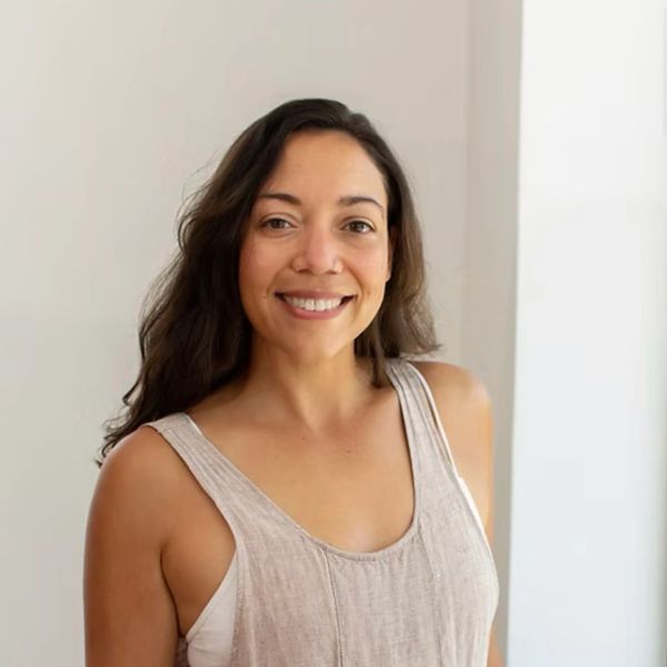 Smiling woman with long hair in a beige sleeveless top.
