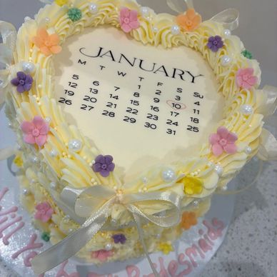 Heart-shaped cake with January calendar and floral decorations.