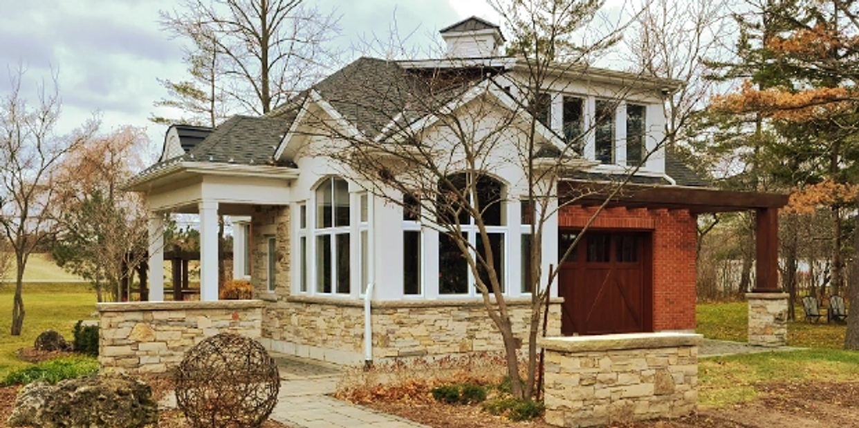 A cozy stone and wood house surrounded by trees and a garden area.