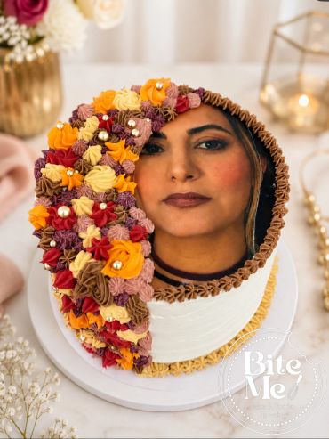 Half-flower decorated cake with a mirror reflecting a woman's face.
