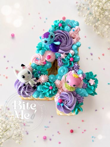 Decorated number 1 cake with colorful frosting and toy figures.