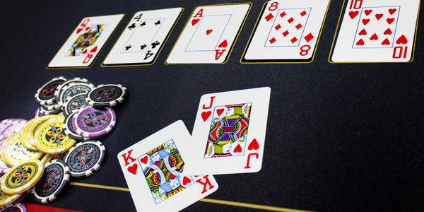 Poker cards and chips on a black table in a casino game.