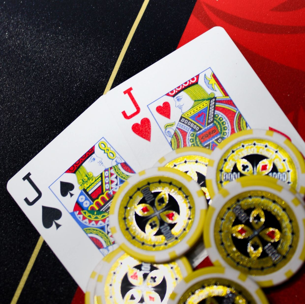Poker chips on Jack of Spades and Jack of Hearts cards.