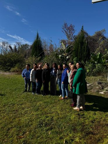 Group of people posing outdoors on a sunny day with greenery and blue sky.