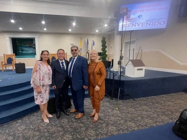 Four adults posing in a church with a welcome sign in the background.