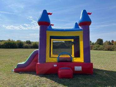 Colorful inflatable bounce house with slide outdoors.