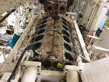 Disassembled large engine block inside a machinery space.