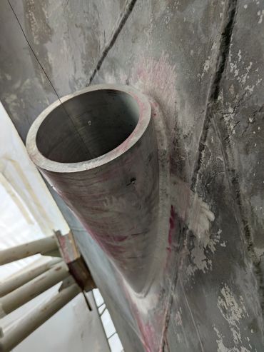 Close-up of a cylindrical metal pipe embedded in a weathered concrete surface.